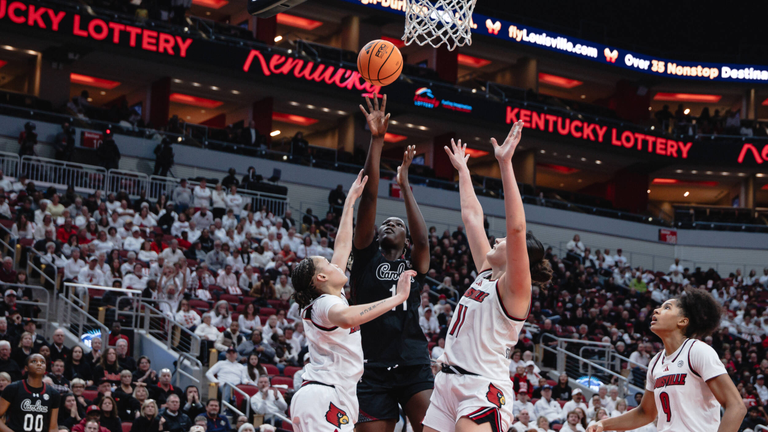 Madina Okot shoots from the left block against two Louisville defenders.