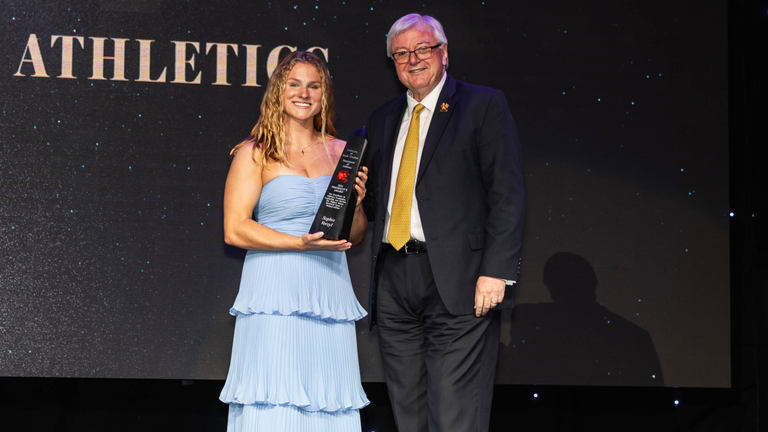 Sophie Verzyl holds the trophy for the President's Award with University President Michael Amiridis