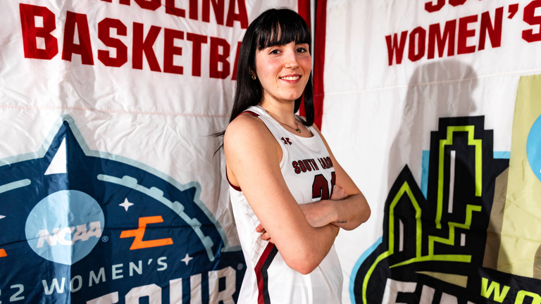 Justine Loubens poses in front of two of South Carolina's women's basketball national championship banners.