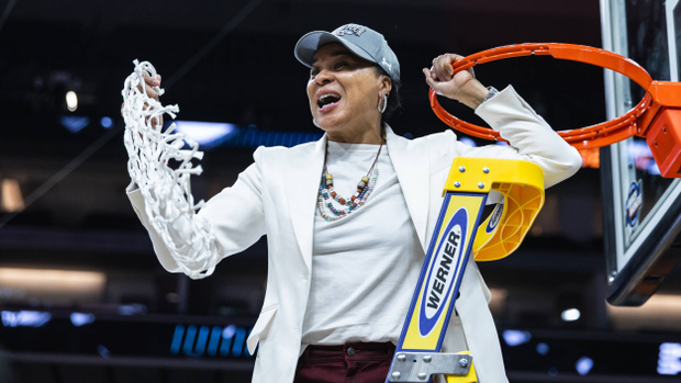 Dawn Staley holds the rim in one hand and the net in the other while celebrating the Gamecocks advancing to the 2026 NCAA Final Four.