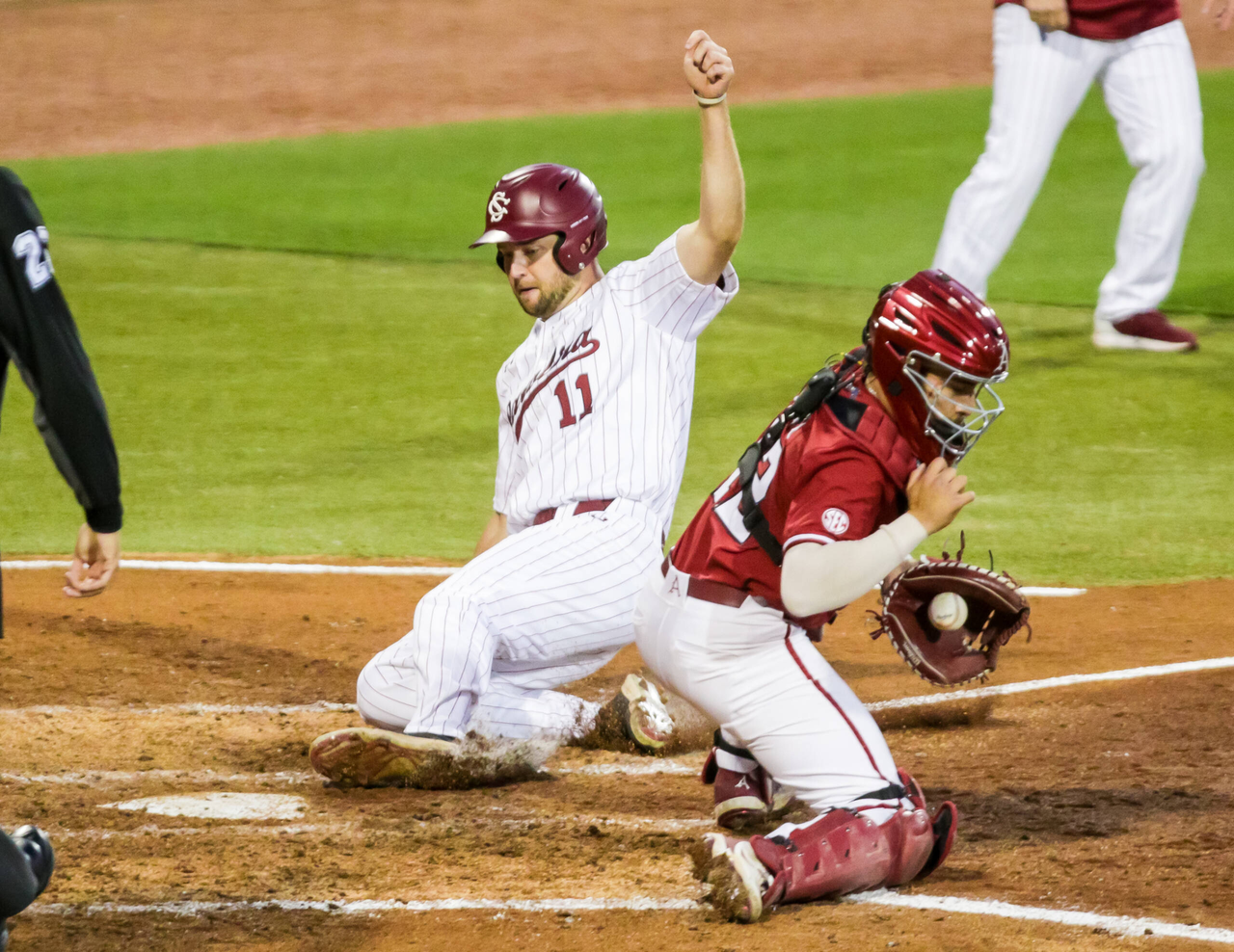 South Carolina Gamecocks outfielder Andrew Eyster (11) slides safely home for a run as Arkansas Razorbacks catcher Casey Opitz (12) takes the late throw during the fourth inning.